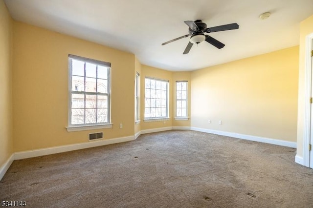 carpeted empty room featuring visible vents, ceiling fan, and baseboards