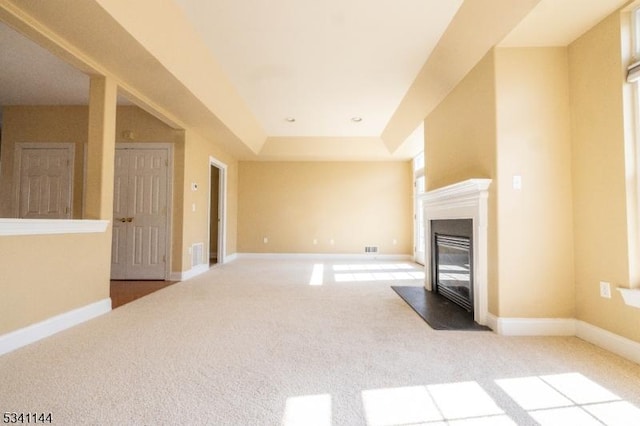 unfurnished living room featuring baseboards, carpet floors, and a glass covered fireplace