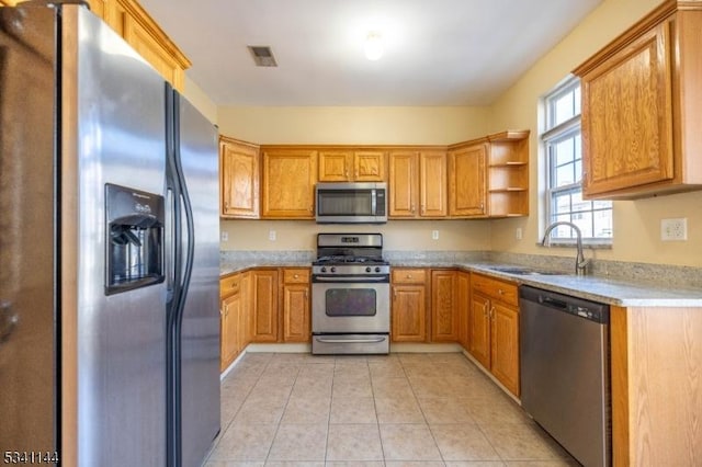 kitchen with brown cabinetry, visible vents, light tile patterned flooring, a sink, and stainless steel appliances