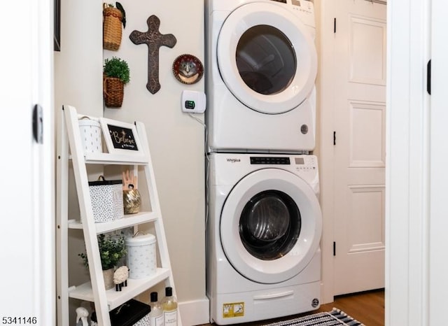 laundry room featuring laundry area, stacked washer and clothes dryer, and wood finished floors