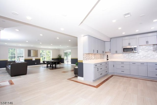 kitchen with visible vents, stainless steel microwave, gray cabinets, light countertops, and backsplash