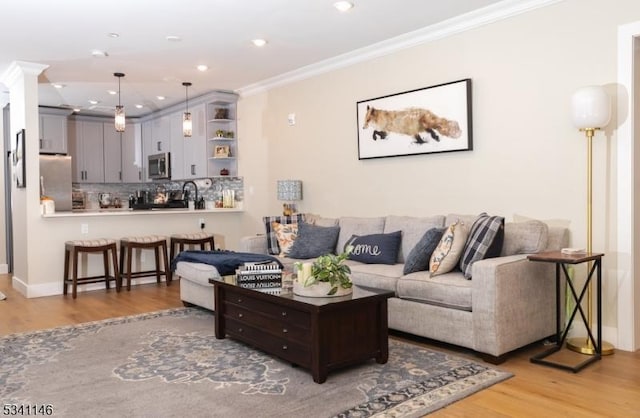 living area with baseboards, ornamental molding, light wood-type flooring, and recessed lighting