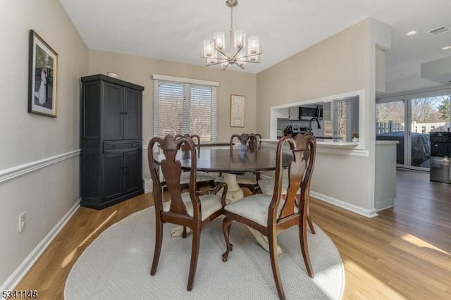 dining room featuring baseboards, a notable chandelier, light wood-style flooring, and visible vents
