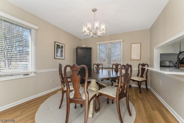 dining space featuring light wood-type flooring, baseboards, a toaster, and a chandelier
