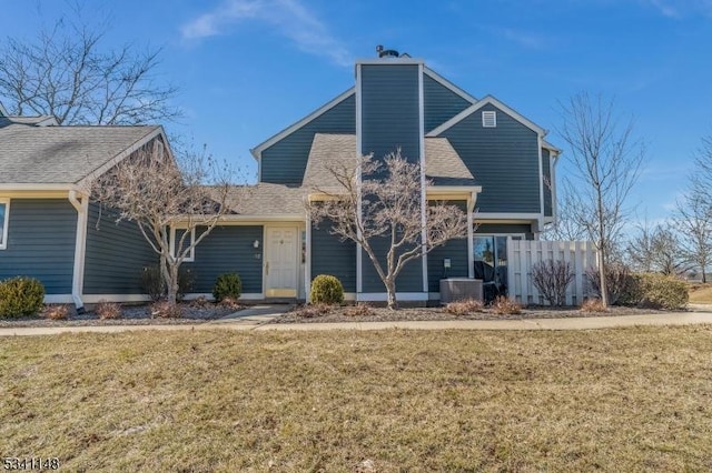 mid-century modern home featuring a front lawn, roof with shingles, central AC, and fence