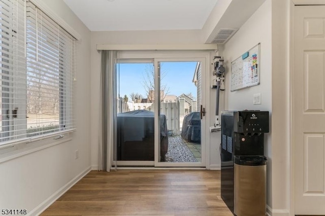 doorway to outside with baseboards, a wealth of natural light, and wood finished floors