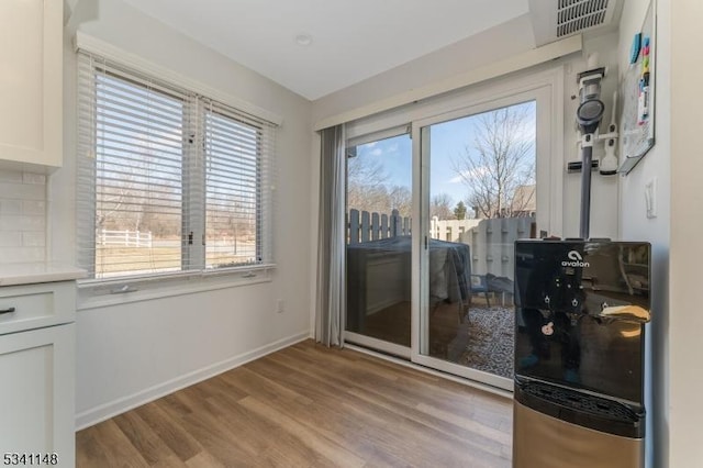 doorway to outside with baseboards, light wood-style flooring, a wealth of natural light, and visible vents