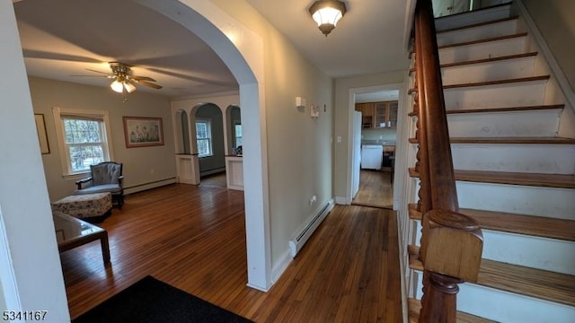 interior space with stairway, baseboard heating, wood finished floors, arched walkways, and a baseboard radiator