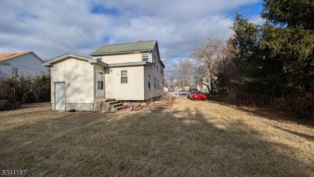 rear view of property featuring entry steps and a lawn