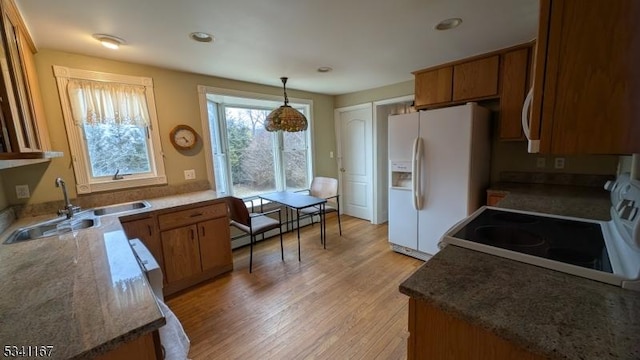 kitchen featuring brown cabinetry, baseboard heating, white appliances, and light wood-style floors