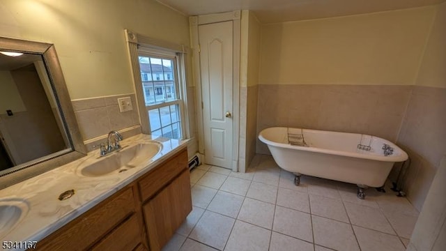full bathroom featuring double vanity, a freestanding bath, tile patterned flooring, a sink, and tile walls