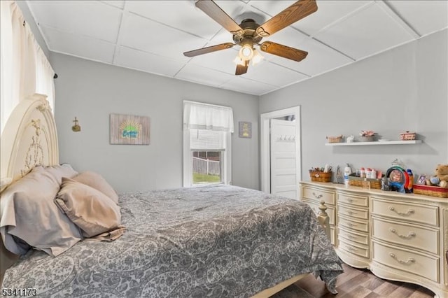 bedroom with a paneled ceiling, a ceiling fan, and wood finished floors