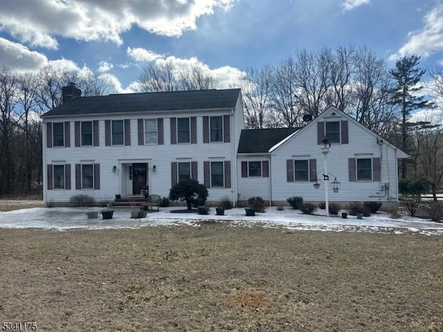 back of house with entry steps, a chimney, and a yard