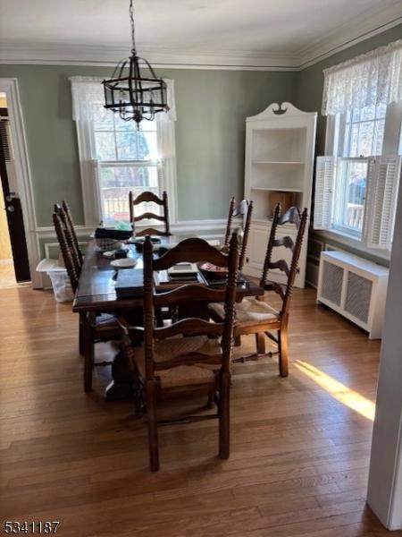 dining space featuring crown molding, radiator heating unit, dark wood-style floors, and a chandelier