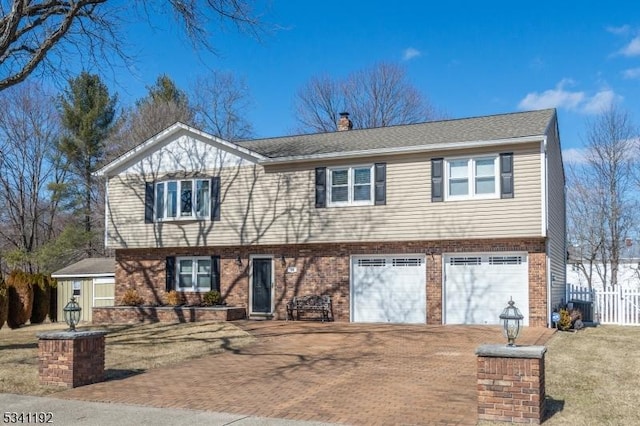 view of front of house featuring brick siding, a chimney, fence, and decorative driveway