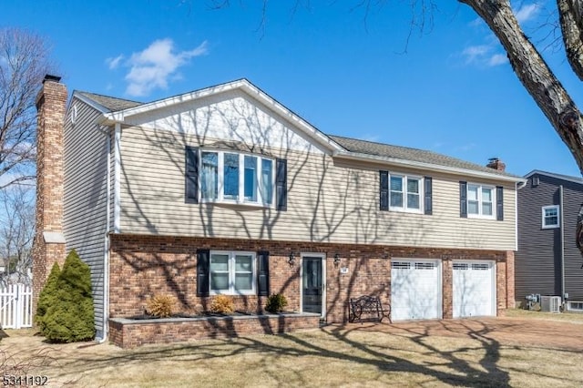 view of front of property with brick siding, driveway, a chimney, and fence