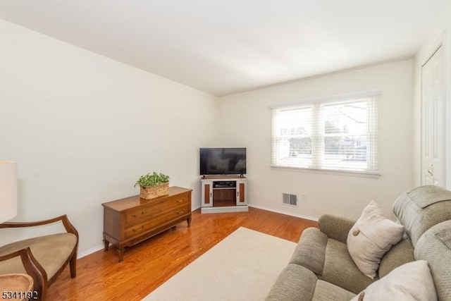 living area with light wood-style flooring, visible vents, and baseboards