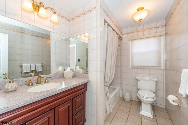 full bathroom featuring toilet, vanity, tile patterned flooring, and tile walls