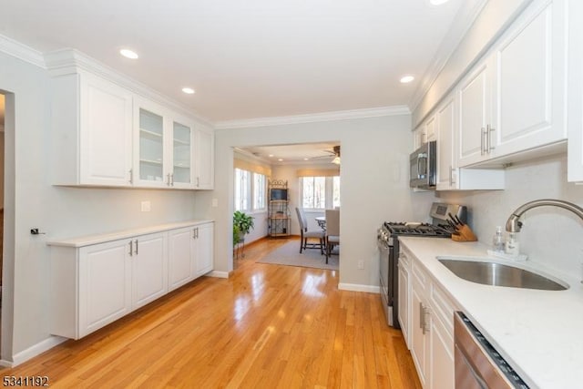 kitchen featuring white cabinetry, stainless steel appliances, a sink, and light countertops