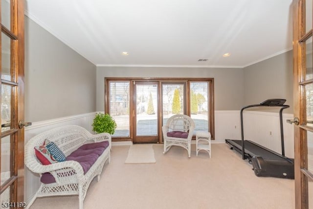 interior space with carpet floors, wainscoting, ornamental molding, and visible vents