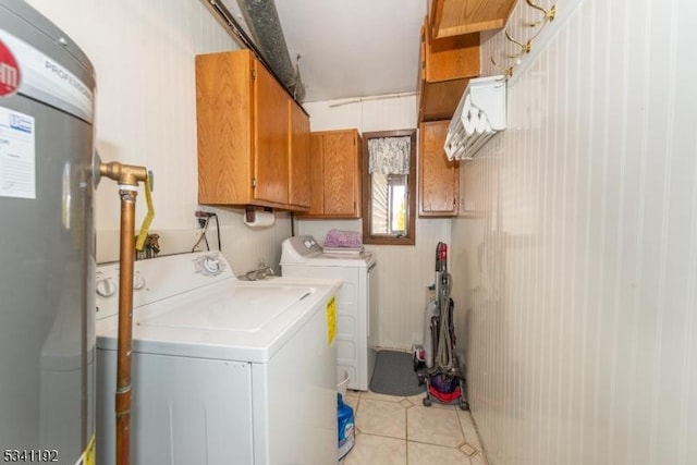 clothes washing area featuring water heater, cabinet space, washing machine and clothes dryer, and light tile patterned floors