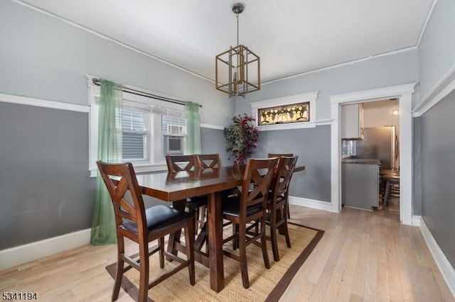 dining room with baseboards, an inviting chandelier, ornamental molding, and light wood finished floors