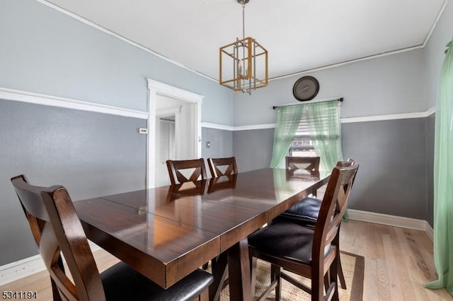 dining room with a notable chandelier, baseboards, crown molding, and light wood-style floors