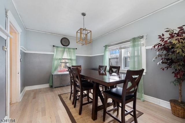 dining room with light wood finished floors, baseboards, an inviting chandelier, and ornamental molding