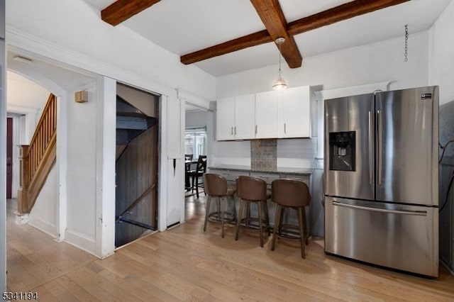 kitchen with decorative backsplash, light wood-style floors, white cabinets, and stainless steel refrigerator with ice dispenser