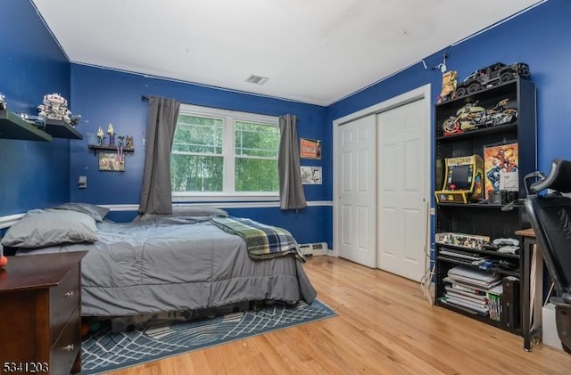 bedroom with a baseboard radiator, a closet, and wood finished floors