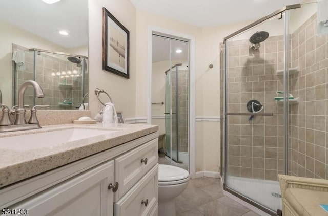 bathroom featuring toilet, a shower stall, and vanity