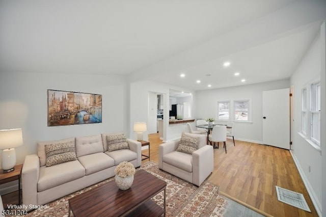 living area with baseboards, light wood-type flooring, visible vents, and recessed lighting