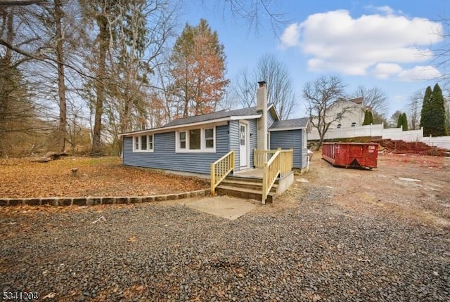 view of front of house with a deck, fence, and a chimney