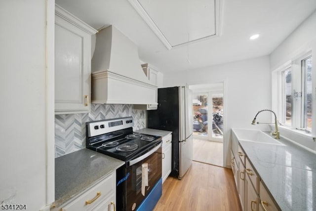 kitchen with custom exhaust hood, plenty of natural light, appliances with stainless steel finishes, and a sink