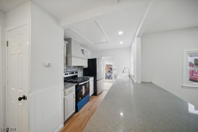 kitchen with light stone countertops, a sink, stainless steel range with electric cooktop, decorative backsplash, and custom range hood