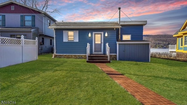 rear view of property featuring a yard, entry steps, and fence