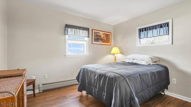 bedroom featuring a baseboard radiator, baseboards, and wood finished floors