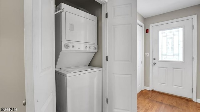 washroom featuring laundry area, baseboards, light wood-style floors, and stacked washer / dryer