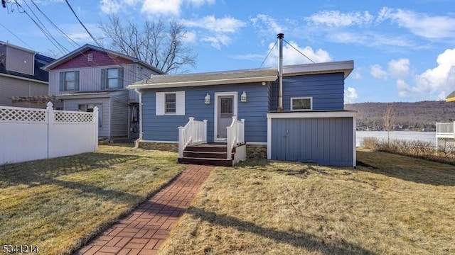 rear view of house featuring fence and a lawn