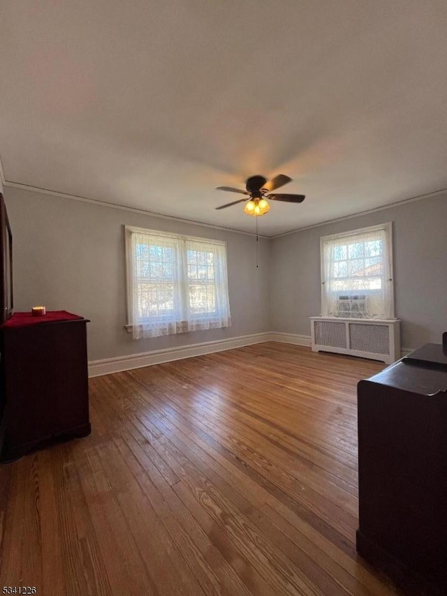 living room with wood-type flooring, baseboards, ceiling fan, and radiator heating unit