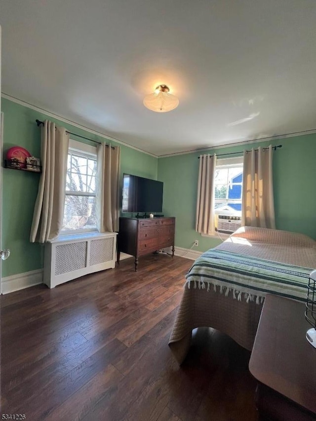 bedroom featuring ornamental molding, multiple windows, radiator heating unit, and wood finished floors