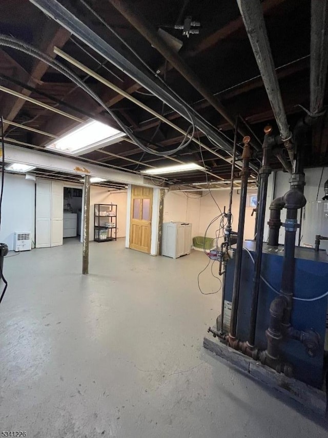 unfinished basement featuring a heating unit and separate washer and dryer