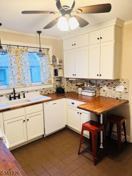 kitchen with crown molding, white cabinets, white dishwasher, a sink, and butcher block countertops