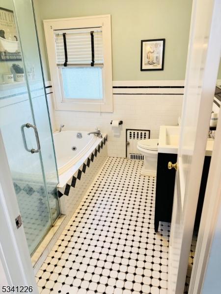 bathroom featuring a garden tub, toilet, vanity, a shower stall, and radiator