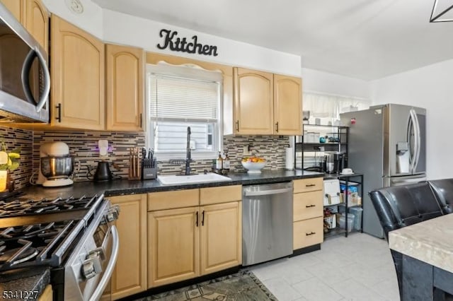 kitchen featuring light brown cabinetry, appliances with stainless steel finishes, backsplash, and a sink