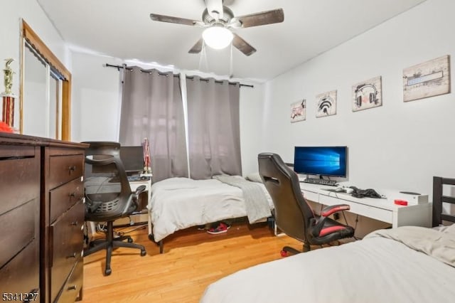 bedroom with light wood-type flooring, ceiling fan, and a closet