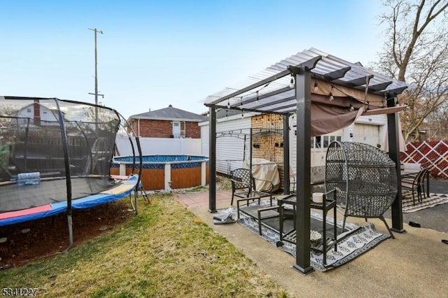 view of yard featuring a trampoline, fence, and a patio