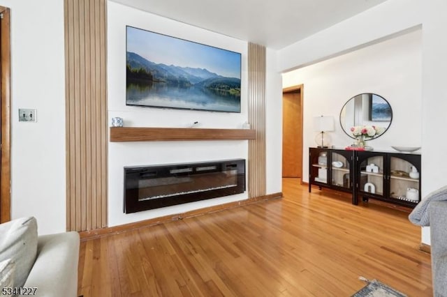 unfurnished living room with wood finished floors and a glass covered fireplace