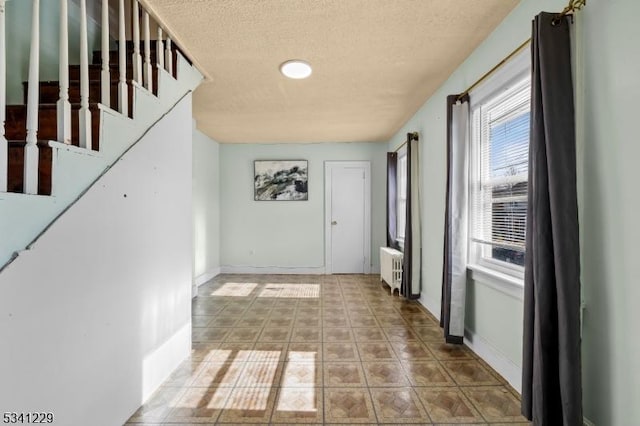 doorway to outside featuring radiator heating unit, stairs, baseboards, and a textured ceiling