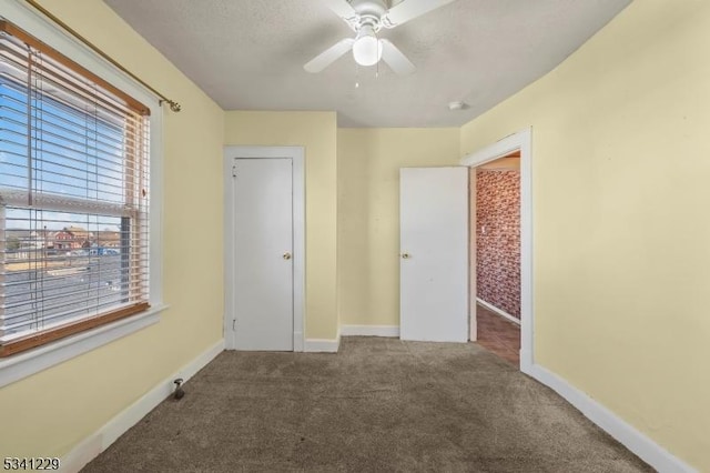 unfurnished bedroom featuring a ceiling fan, carpet, a textured ceiling, and baseboards